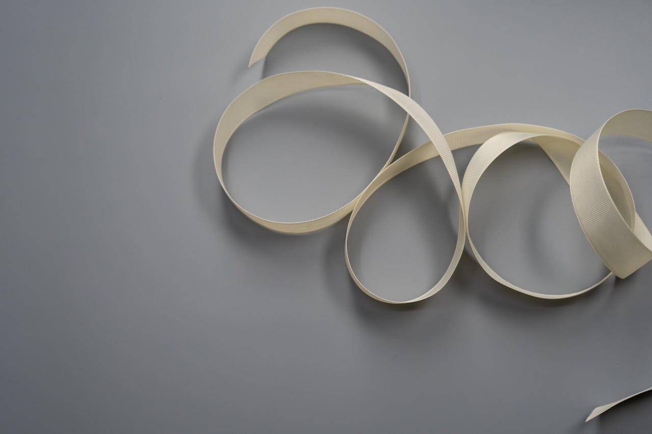 A soft white ribbon elegantly arranged on a smooth grey surface, perfect for design projects.