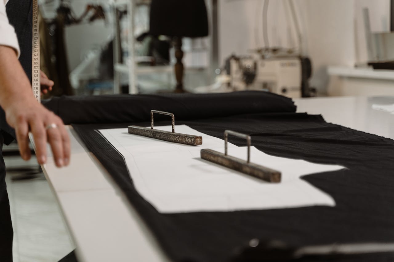 Close-up of a tailor measuring fabric with a tape in a sewing studio.
